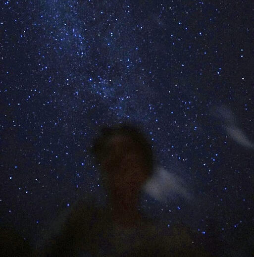 the silhouette of storm from the shoulders up against the milky way on a long exposure shot